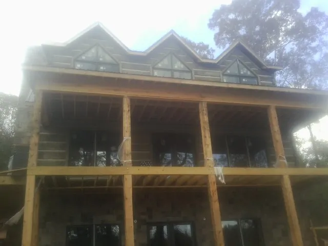 Dormers and porch framing on a large log home under construction — Roof Coating work by our crew in Conyers
