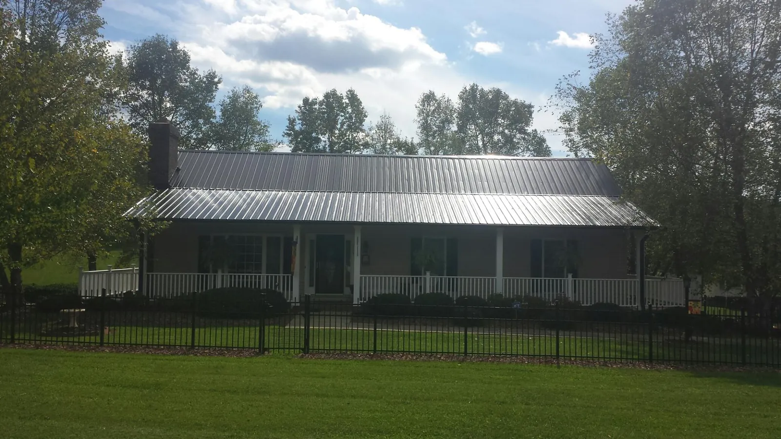 Gray metal roof on a brick ranch with a full width front porch — Gutter Guard Installation work by our crew in Conyers