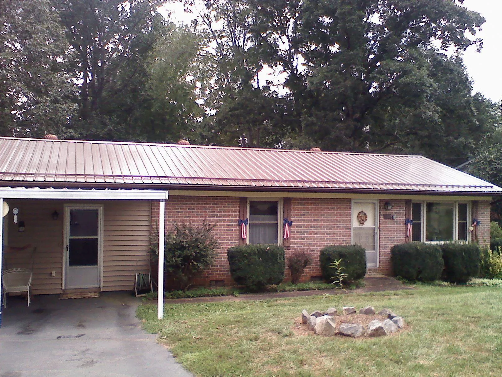 Bronze metal roof and carport on a brick ranch home — Roof Repair work by our crew in Conyers