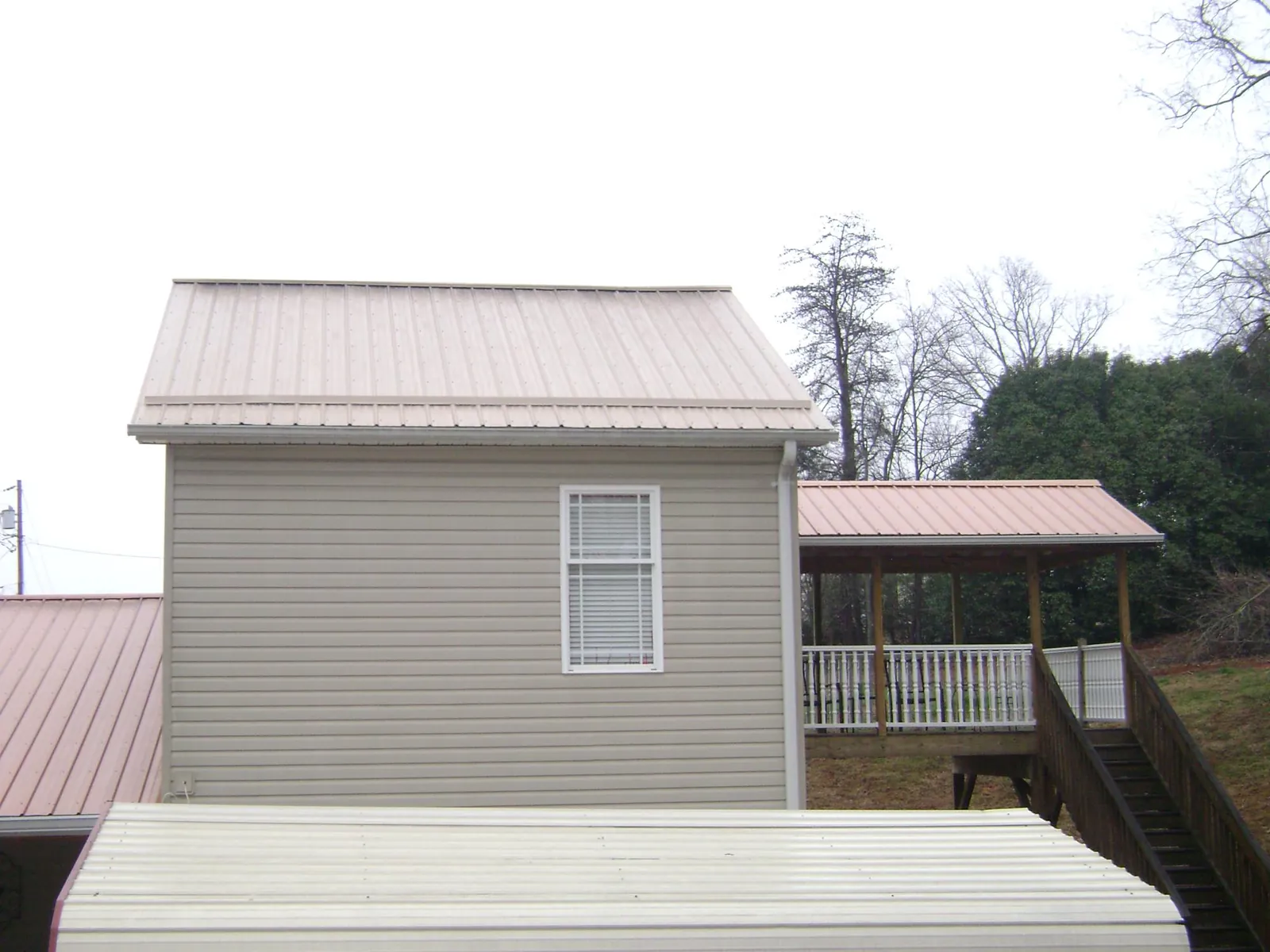 Tan metal roofs on a two story addition and attached porch, from a Roof Replacement job in Conyers