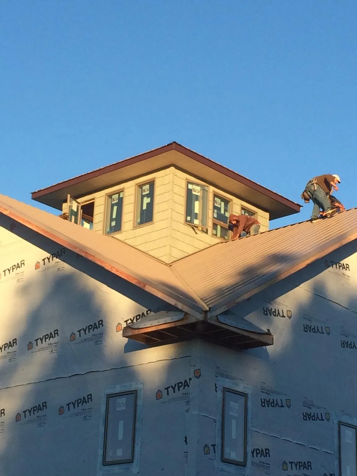 Roofers working around a rooftop cupola on a new metal roof at sunset — Roof Waterproofing in Conyers by Roofing Brothers